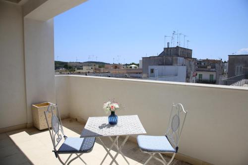 a table and chairs on a balcony with a vase of flowers at Arcadia penthouse appartment Otranto in Otranto
