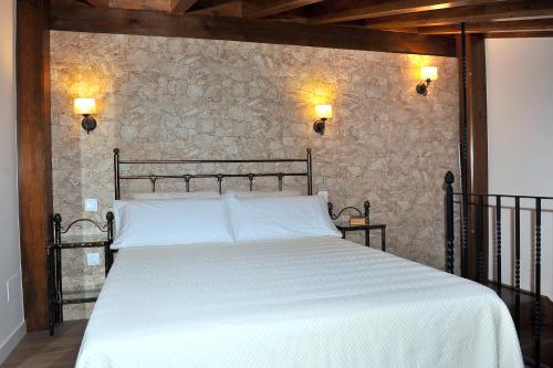 a bed in a room with a stone wall at Alojamiento Colmenar de Oreja Plaza Mayor in Colmenar de Oreja
