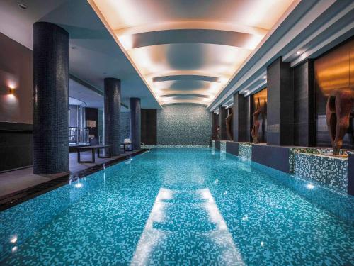 a large swimming pool in a hotel with a ceiling at Quay West Suites Melbourne in Melbourne