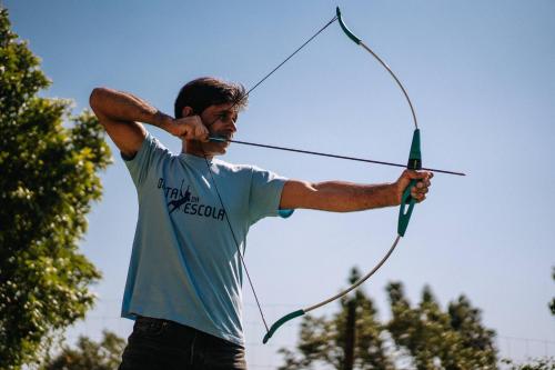 a man is holding a bow and arrow at Casas de Pedra - Quinta da Escola in Alvados