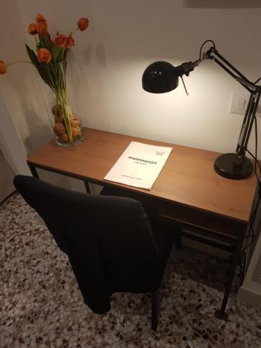 a desk with a lamp and a chair and flowers at MammaDada charm rooms in Bari