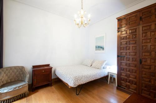 a room with a bed and a chair and a door at Beach & City - Neighbourhood of Gros in San Sebastián