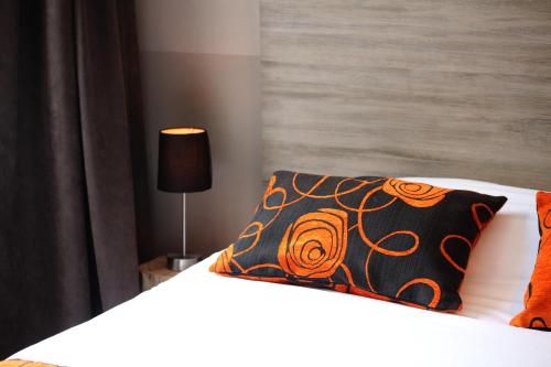 a bed with a black and orange pillow on it at Logis Hostellerie de l'Abbaye in Celles-sur-Belle