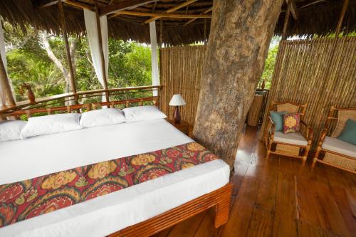 a bedroom with two beds and two chairs at Treehouse Lodge in Yucuruche