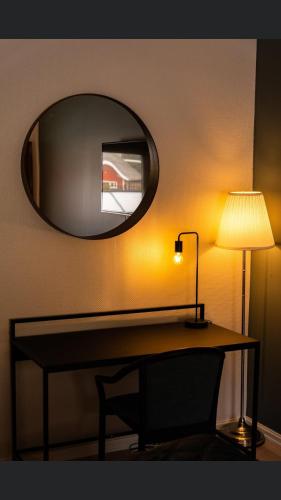 a table with a lamp and a mirror on a wall at Fabel kafé og Motell in Dale