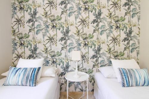 a bedroom with two beds with palm trees wallpaper at Casa bien equipada para 8 personas in Pasito Blanco