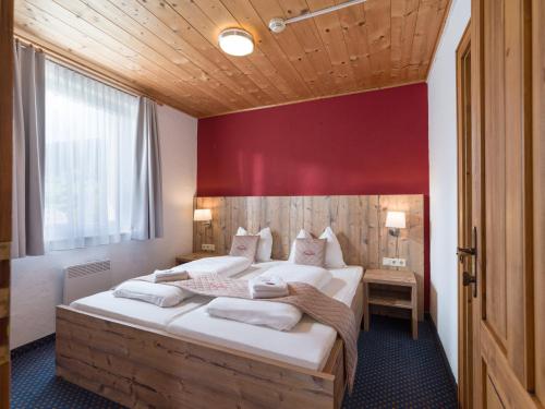 a bedroom with a large bed with a red wall at Haus Tirol in Brixen im Thale
