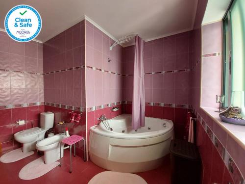 een roze badkamer met een bad en een toilet bij Nelocas House in Ponta Delgada