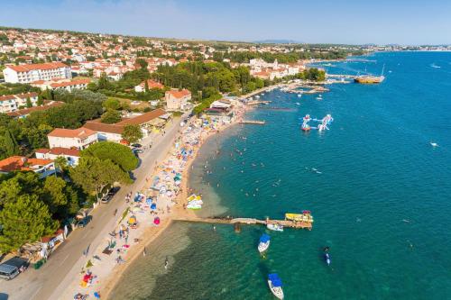 an aerial view of a beach with people in the water at Merita Apartments with Pool in Sveti Filip i Jakov
