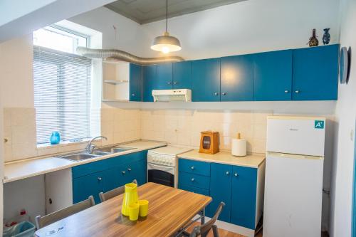 uma cozinha com armários azuis e uma mesa de madeira em Cozy House with Flowery Courtyard in Notable Location in Ilha de Rhodes