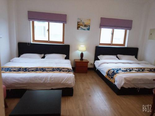 2 Betten in einem Zimmer mit 2 Fenstern in der Unterkunft Jinsha Haiyunbian I Homestay in Insel Nangan