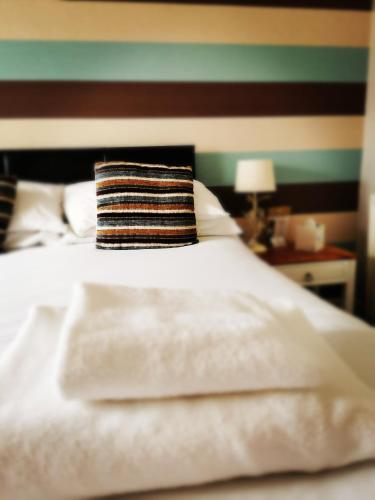 a white bed with a striped pillow on it at The Manor House Inn in Shotley Bridge