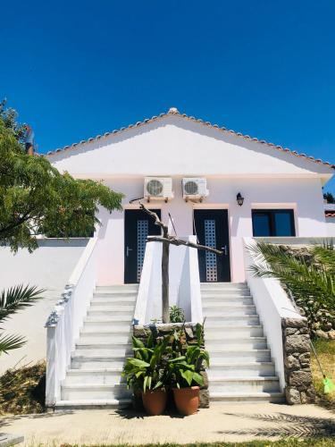 a white house with stairs and potted plants at Kirkos Apartments in Kamariotissa