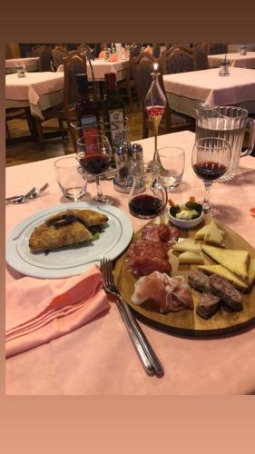 a table with two plates of food and glasses of wine at Beohotel in San Lorenzo in Banale
