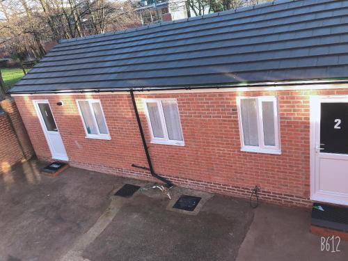 a red brick building with a black roof at Flat 1 - Entire Modern Studio with en-suite and free Parking close to QMC, City centre & Notts Uni in Nottingham