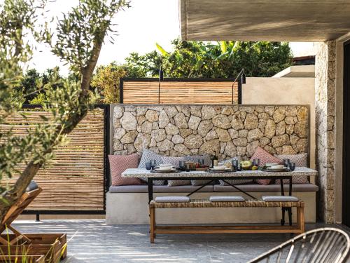 a patio with a table and a stone wall at Mimi and Coco Villas Corfu in Paramonas
