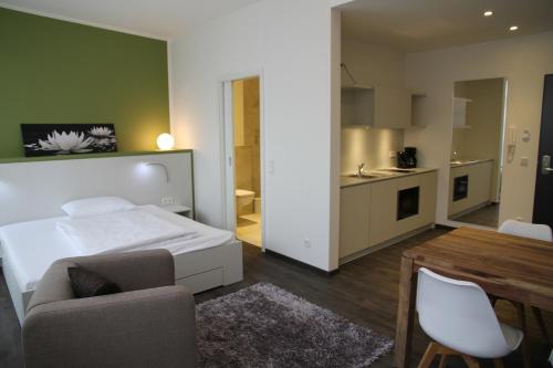 ein Schlafzimmer mit einem Bett und einem Tisch sowie eine Küche in der Unterkunft Boardinghouse Offenbach Service Apartments in Offenbach