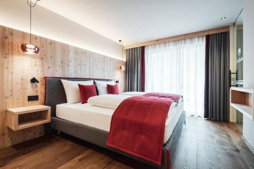 Un dormitorio con una cama con una manta roja. en Batacör - Natures Heartbeat, en San Vigilio Di Marebbe