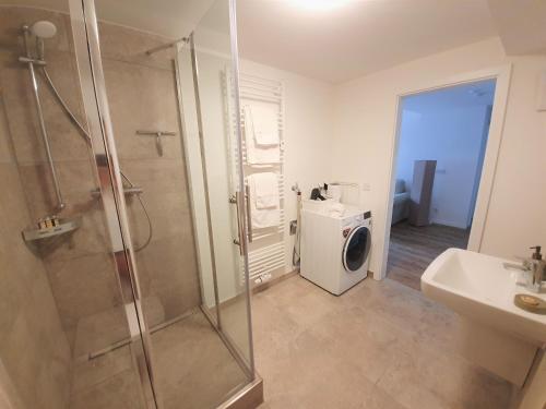 a bathroom with a shower and a washing machine at PB Ferienwohnungen - FeWo 1 - Stilvoll eingerichtetes Apartment im Herzen Senftenbergs in Senftenberg