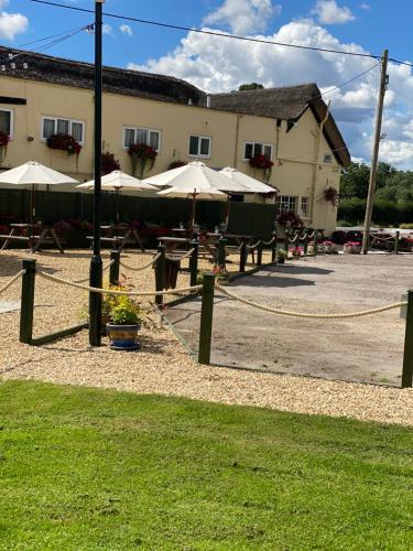 a patio with tables and umbrellas in front of a building at Greyhound Country Inn in Honiton
