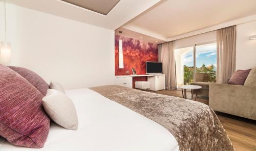 um quarto de hotel com uma cama e um sofá em Insotel Tarida Beach Resort & SPA em Cala Tarida