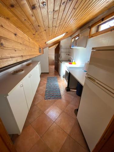 una cucina con armadi bianchi e soffitto in legno di Mansarda Villa Simonetta a Esino Lario