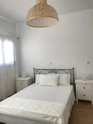 a white bedroom with a bed and a chandelier at Vegera Apartment 'Sofrano', Stavros Donoussa in Donoussa