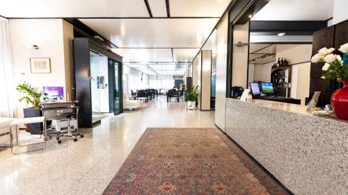 an office lobby with a reception desk and a corridor at Hotel Lis in Asti