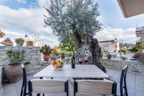 Villa Olive Tree في بيتسيديا: طاولة مع وعاء من الفواكه وزجاجة من النبيذ
