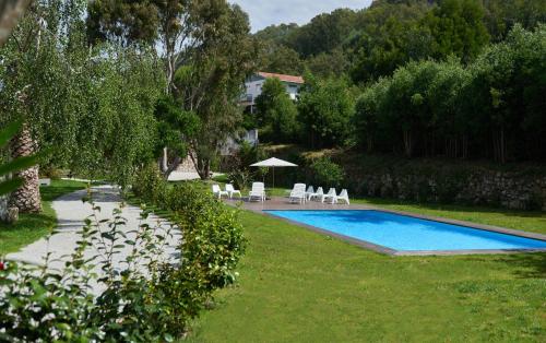a swimming pool in a yard with chairs and an umbrella at Casa De Crespins Casa de Campo Lda in Cristelo