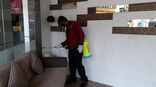 a man standing next to a wall holding a yellow object at Hotel Pearl in Vadodara