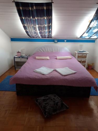 a bedroom with a pink bed with two towels on it at Apartment Jadranka in Malinska