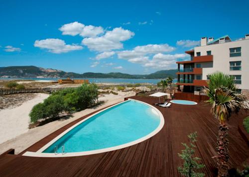 a swimming pool next to a beach and a building at Troia Residences - Apartamentos Praia in Troia