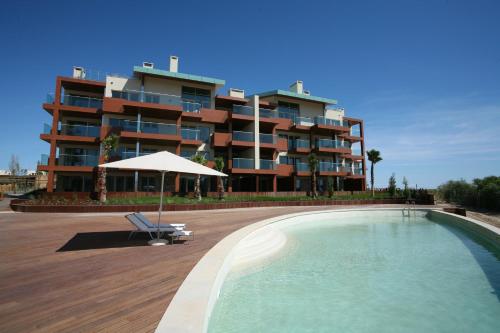 a hotel with a swimming pool and a building at Troia Residences - Apartamentos Praia in Troia