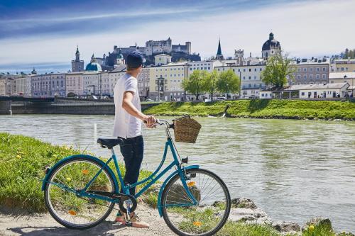 a man standing next to a bike in front of a river at Boutique-Gasthof Ueberfuhr in Salzburg