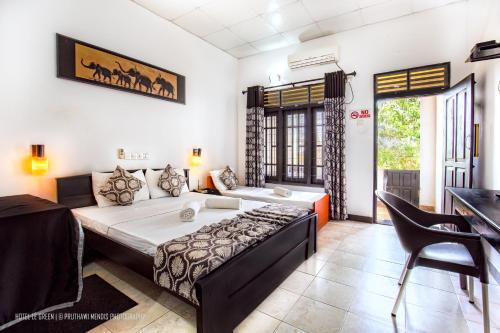 una camera con un grande letto e una scrivania di Hotel Le Green Udawalawe a Udawalawe