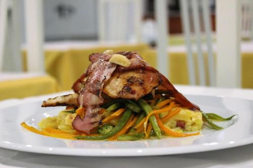 a plate of food with meat and vegetables on a table at Aparthotel Calema Avenida Jardim in Monte Gordo
