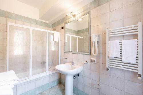 a white bathroom with a sink and a mirror at Hotel La Piazzetta in Castellammare del Golfo