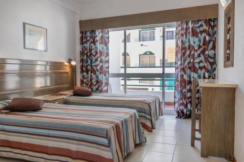 モンテ・ゴルドにあるアパートホテル カレマ アベニーダ ジャルディンのベッド2台と窓が備わるホテルルームです。