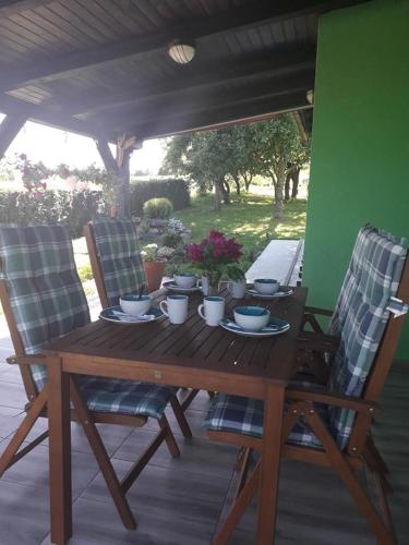 a wooden table with two chairs and a table with dishes on it at Ruralna kuća za odmor Viktorija in Čaglin