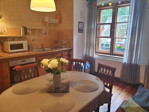 a kitchen with a table with a vase of flowers on it at Apartament Zieleniec in #N/A
