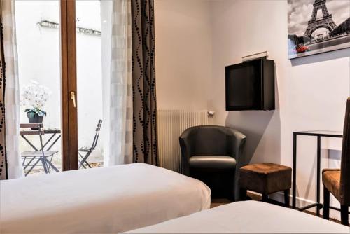 a hotel room with two beds and a chair and a television at Hôtel du Maine in Paris