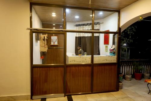 a person sitting at a counter behind a glass door at The LEEF INN 500Ms from Nakki Lake in Mount Ābu