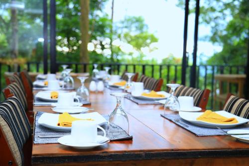 a long wooden table with plates and glasses on it at Spring Villas Kandy in Kandy