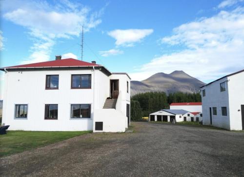 a white house with a red roof with mountains in the background at Setberg Guesthouse in Nesjum