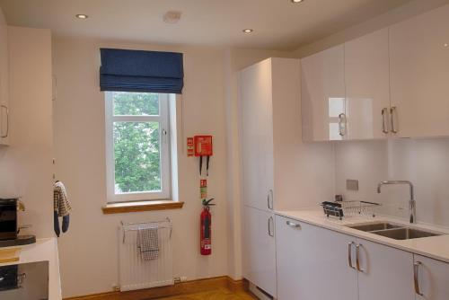 una cocina con armarios blancos y una ventana en Royal Golf Apartments en Dornoch