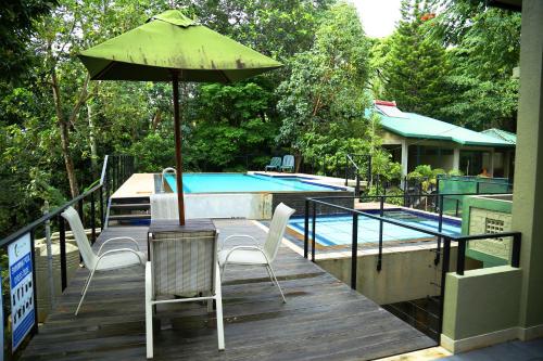 a patio with a table and an umbrella and a pool at Spring Villas Kandy in Kandy