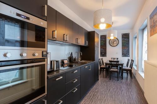 une cuisine avec des armoires noires et une table à manger dans l'établissement Paysages Normands, à Honfleur