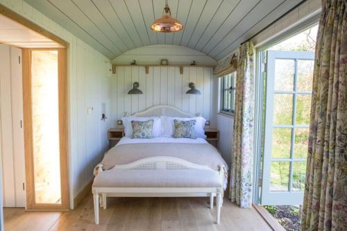 een slaapkamer met een bed en een groot raam bij Perkins luxury shepherd huts in Nottingham