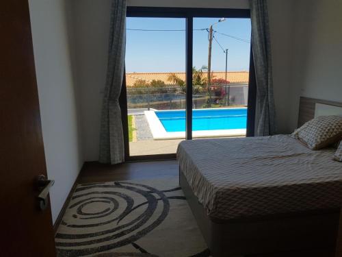 a bedroom with a bed and a view of a swimming pool at migs'place in Arco da Calheta